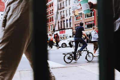 People riding bicycle on street against building in city