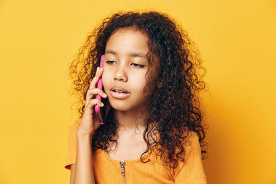 Portrait of young woman against yellow background