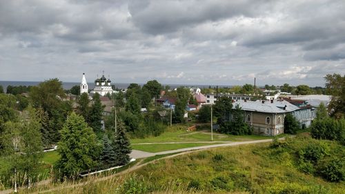 Trees and buildings in city against sky