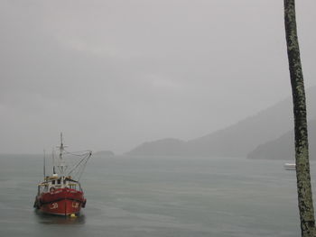 Boats in sea with mountain range in background