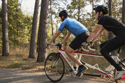 Visually impaired female triathlete training on tandem bicycle with her guide and coach