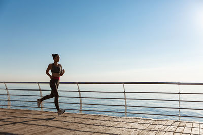 Man standing on railing against sea