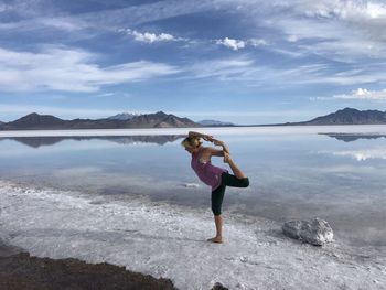 Full length of man on rock in lake against sky