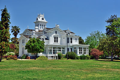 Lawn by building against blue sky