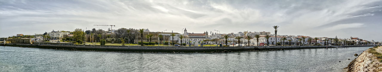 Panoramic shot of buildings by river against sky