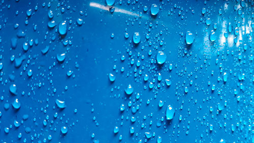 Full frame shot of raindrops on blue glass