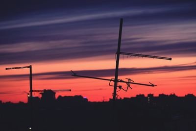 Silhouette cranes against sky during sunset