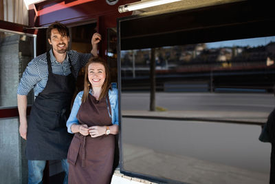 Portrait of male and female owners standing at store entrance