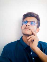 Portrait of young man looking away against wall