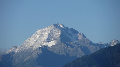 Low angle view of snowcapped mountains against clear blue sky