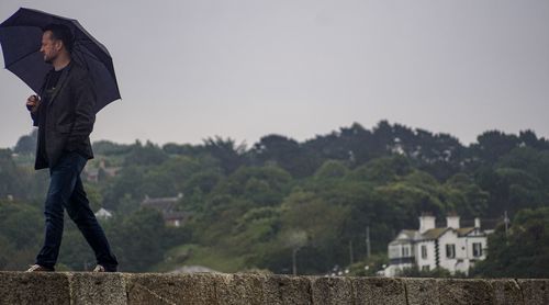 Man standing by wall against clear sky