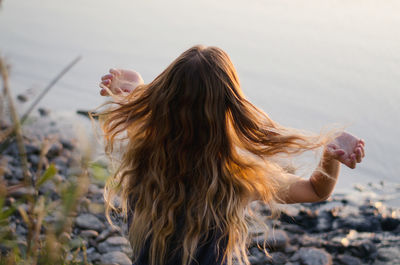 Rear view of woman sitting by lake