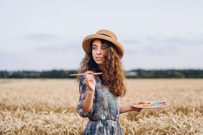 Young woman wearing hat while standing on field