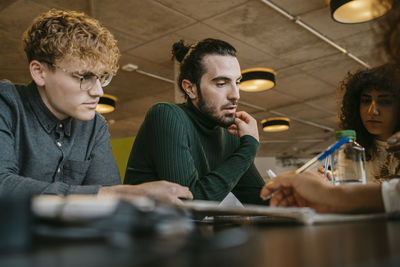 Young multiracial students sitting at table while studying together in cafeteria