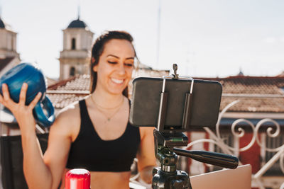 Young sporty fit woman coach doing online lessons through video call on her mobile phone 