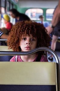 Portrait of cute girl sitting on seat in bus