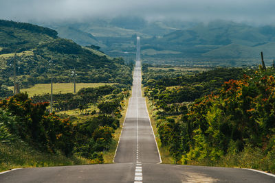 High angle view of empty road leading towards mountains against sky