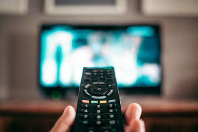 Close-up of hand holding remote control at home