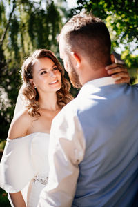 Newlywed couple embracing while standing outdoors