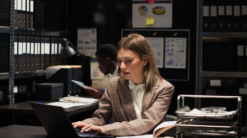 Side view of young woman using laptop at cafe