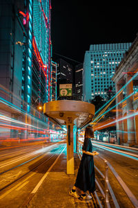 Light trails on street against illuminated buildings in city at night