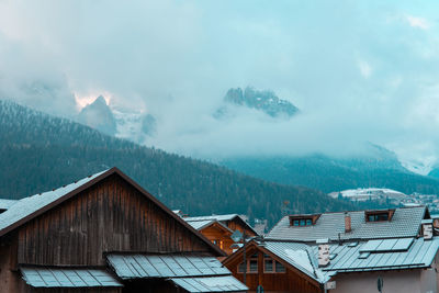 Houses by mountain during foggy weather