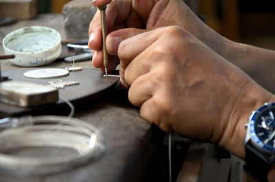 Jeweler making silver jewelry using a screwdriver