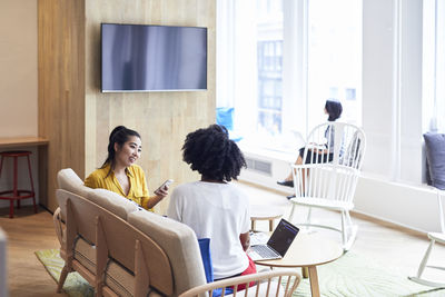 Businesswomen looking at female colleague with coworker sitting in background