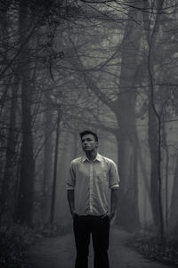 Full length portrait of young man standing in forest during winter