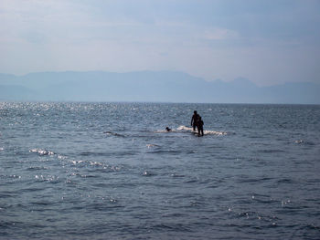 People swimming in sea against sky