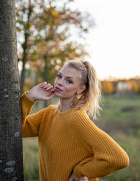 Young woman standing by tree against plants