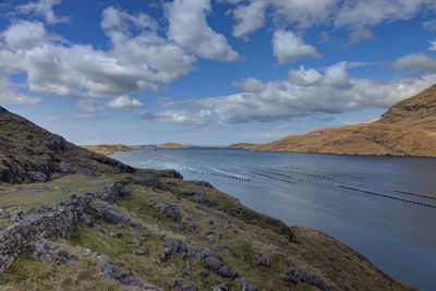 Mussel farming in lake amidst mountain against sky