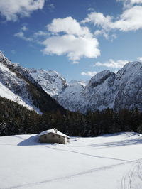 Cottage with snowcapped mountains against sky