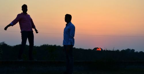 Silhouette of woman standing at sunset