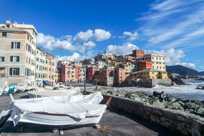 Houses by buildings in city against sky