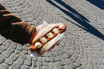 A sausage sandwich in a man's hand.