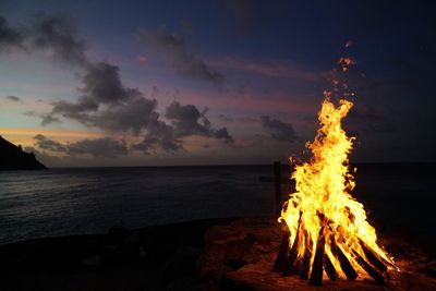Bonfire on beach against sky at dusk