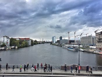 People on river by city against sky