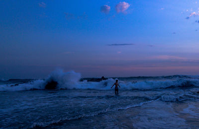 People enjoying in sea against sky during sunset