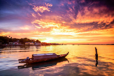 Boats moored on sea against sky during sunset