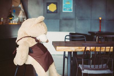 Stuffed toy on chair at table in cafe