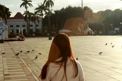Rear view of woman with palm trees against sky