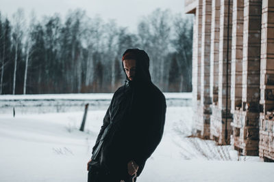 Man standing in snow against trees during winter