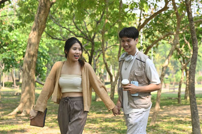 Portrait of smiling couple standing against trees