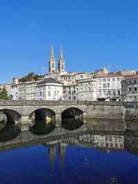 Arch bridge over canal and buildings against blue sky