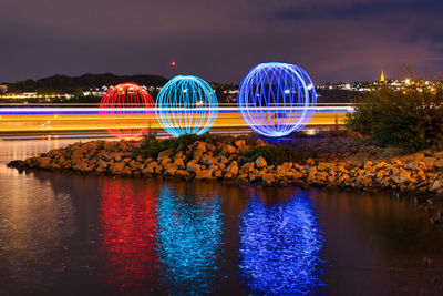 Light trails in lake against sky at night