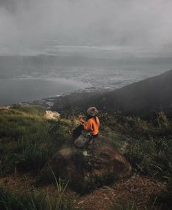 High angle view of woman sitting on rock against landscape