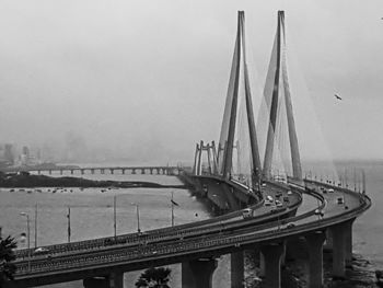 Bridge over river in city against sky