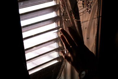 Close-up of hand holding glass window at home