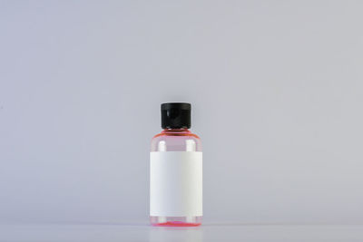 Close-up of empty bottle with sticky label against white background